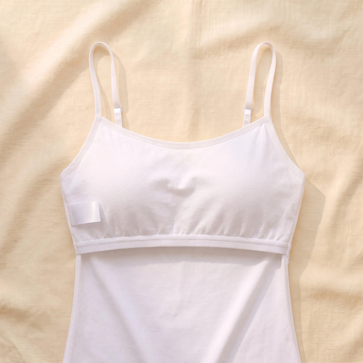 Inside of the Cloud white Kischt Aurelle tank top, turned inside out: the built-in shelf bra is fully covered by a smooth fabric lining with a soft elastic band