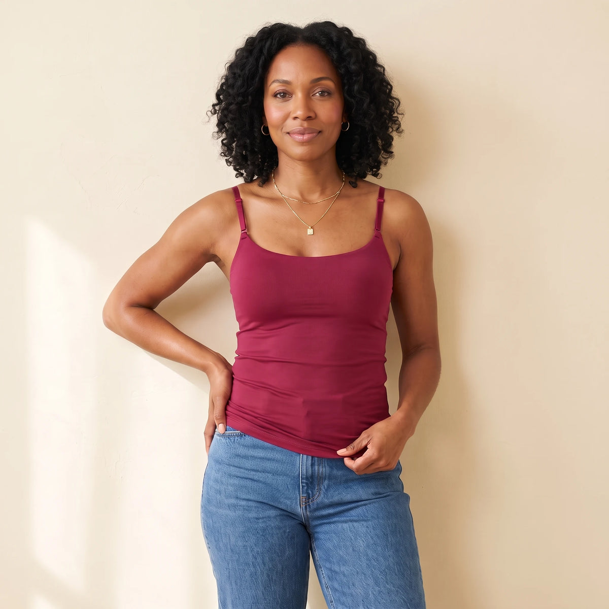 Woman in her 40s wearing the seamless Kischt Aurelle built-in bra tank top in Cerise burgundy with high-waisted jeans