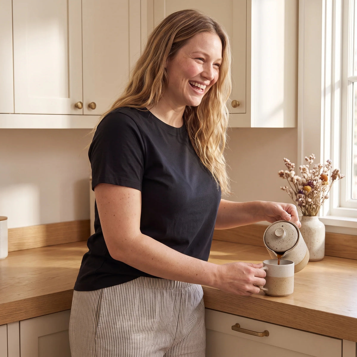 Laughing mum pouring coffee in her kitchen in a black T-shirt over the Noir black Kischt Camille balconette bra