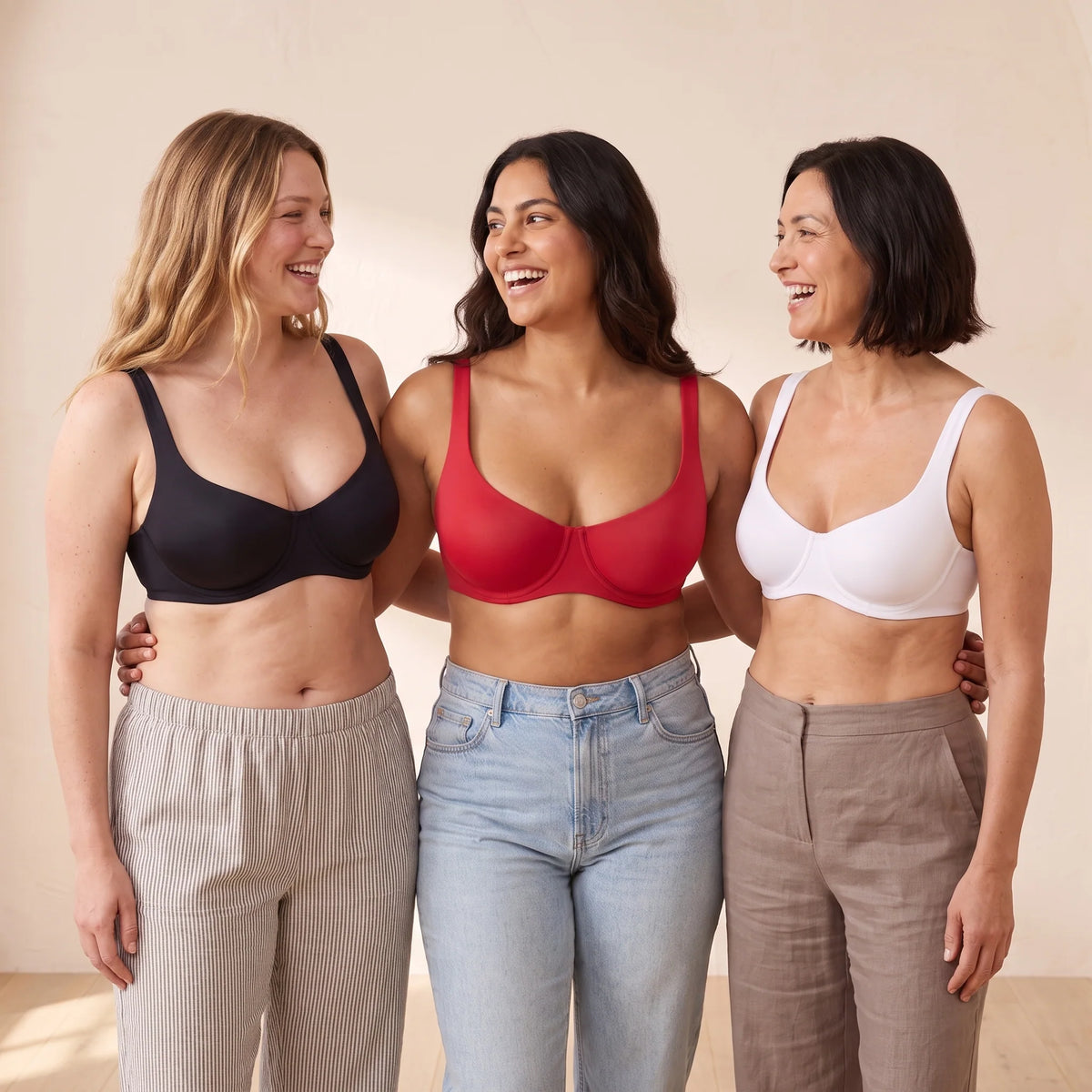 Three women wearing Kischt Camille unlined balconette bras in Noir black, Cerise red and Blanc white