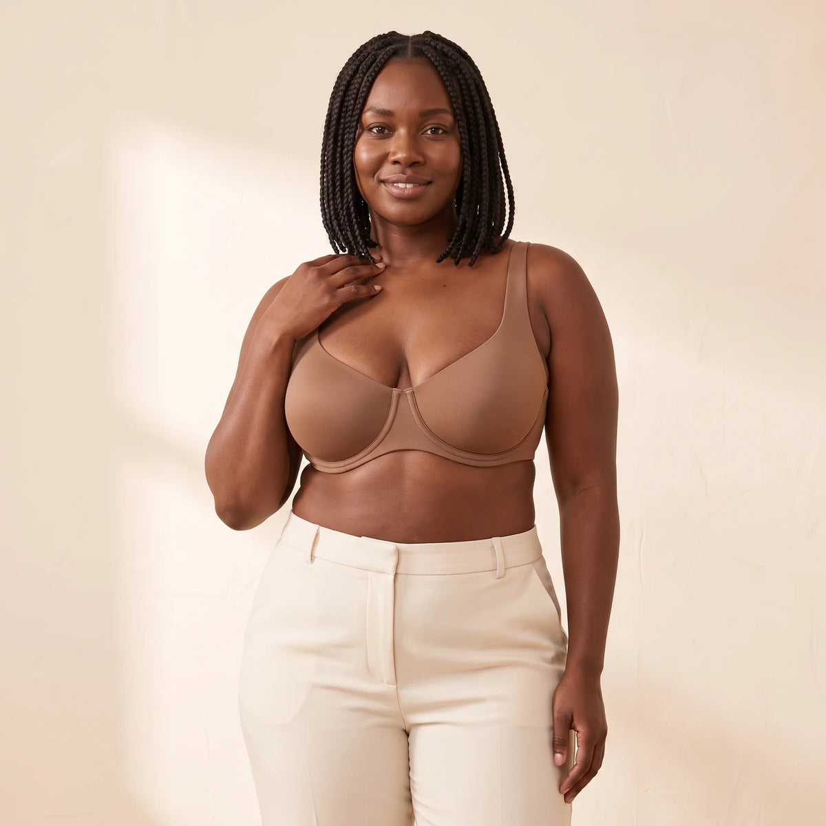 Woman with box braids wearing the Kischt Camille unlined balconette underwire bra in Mocha brown with cream trousers