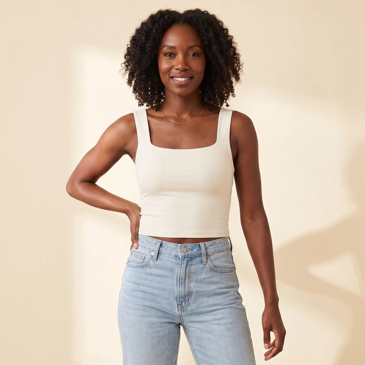 Woman in her 30s wearing the Kischt Elodie square neck crop tank top with built-in bra in Ivoire ivory with high-waisted jeans