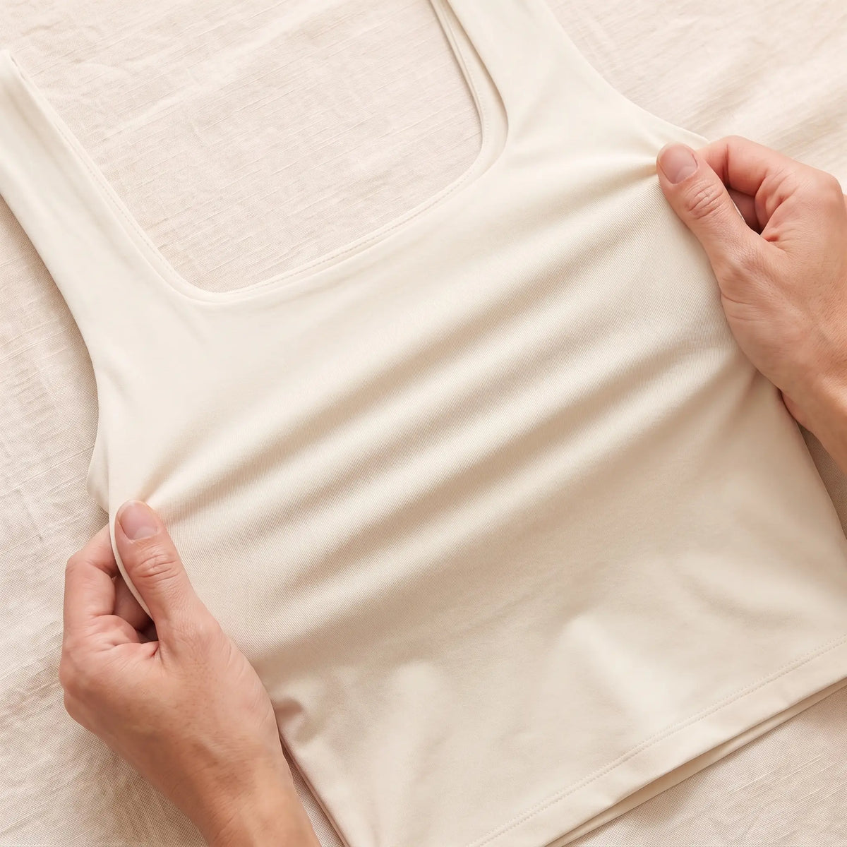 Hands stretching the smooth, soft knit of the Ivoire ivory Kischt Elodie crop tank