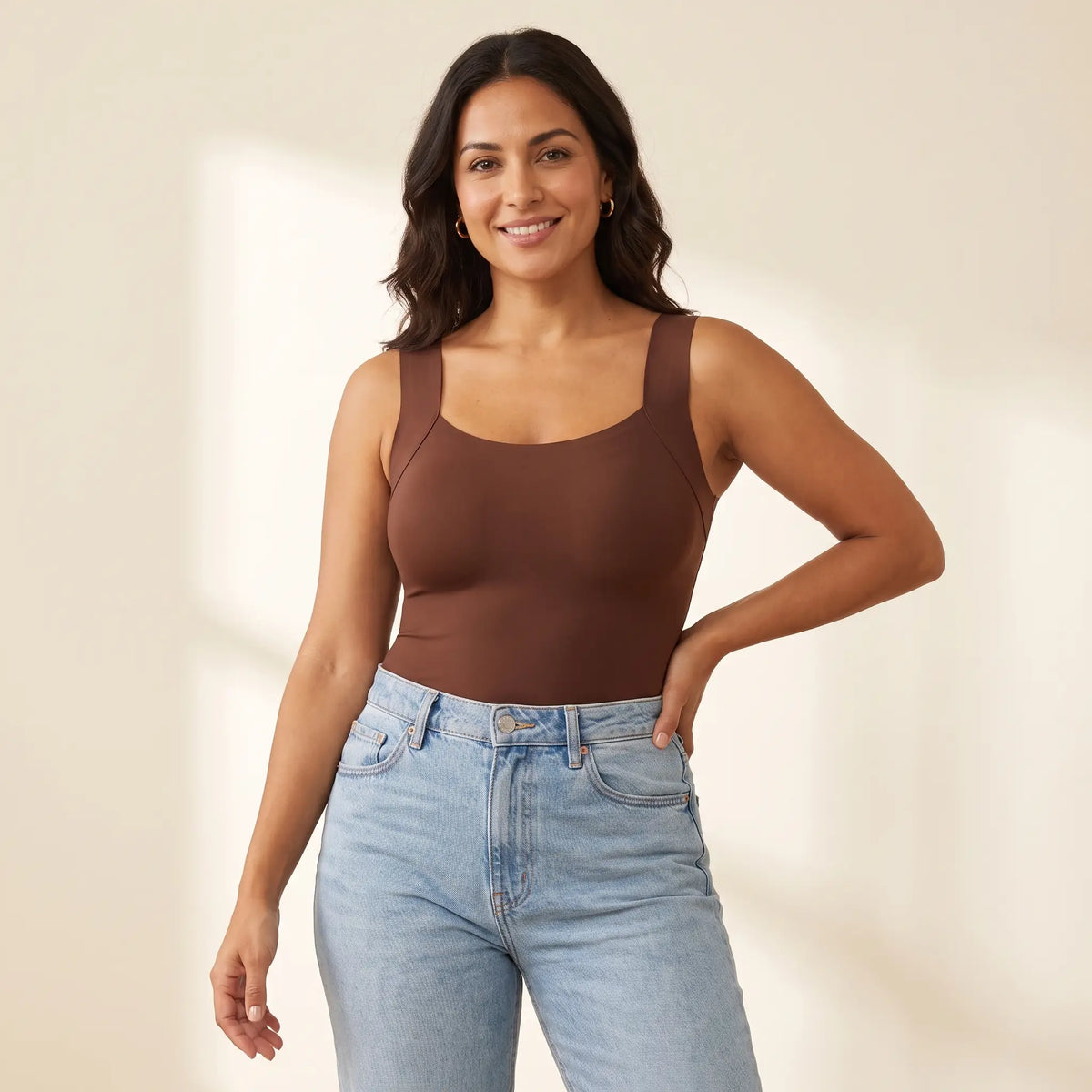 Woman in her 30s wearing the Kischt Estelle seamless built-in bra tank top in Mocha brown with high-waisted jeans