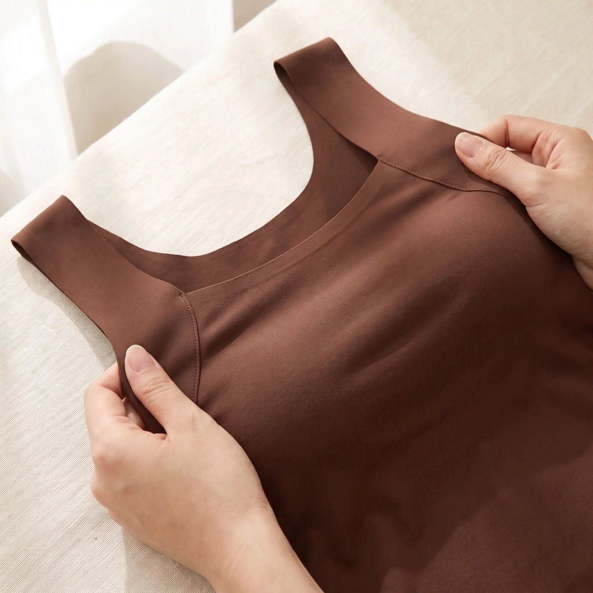 Hands stretching the smooth seamless knit of the Mocha brown Kischt Estelle tank top