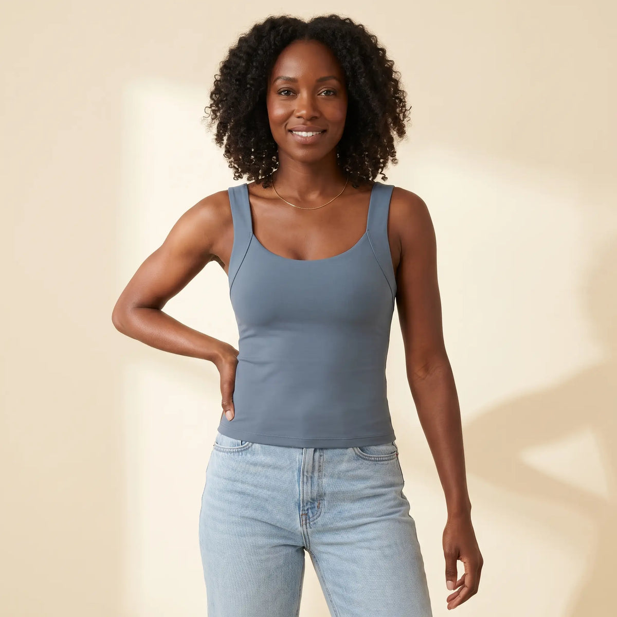Woman in her 30s wearing the Kischt Estelle seamless built-in bra tank top in Slate blue-grey with high-waisted jeans