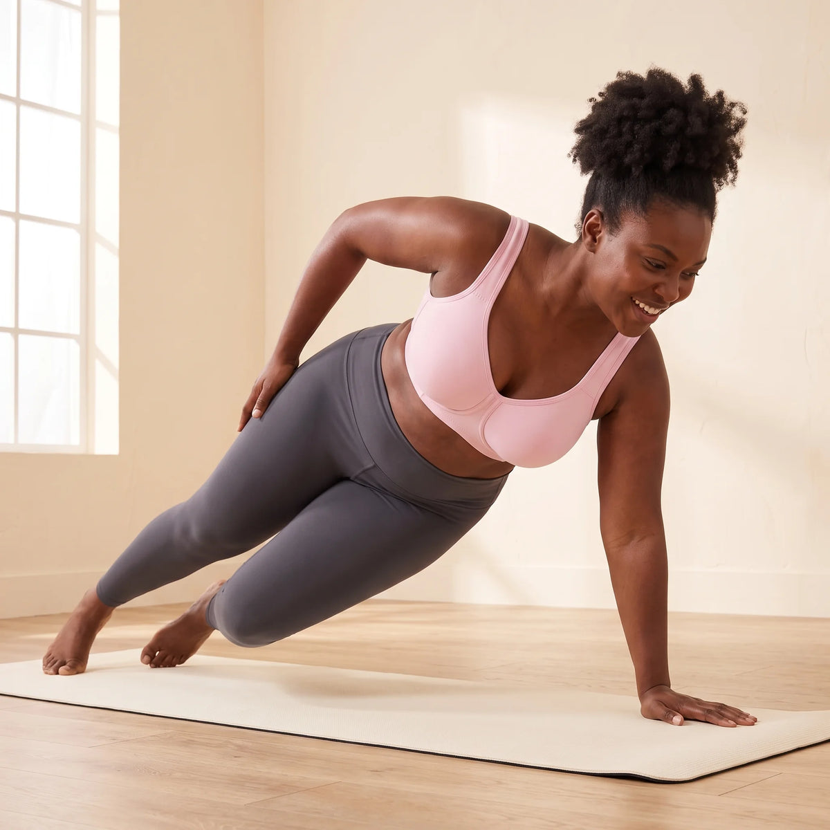 Woman in a side plank on a yoga mat wearing the Blush pink Kischt Léonie sports bra, which keeps a full bust secure