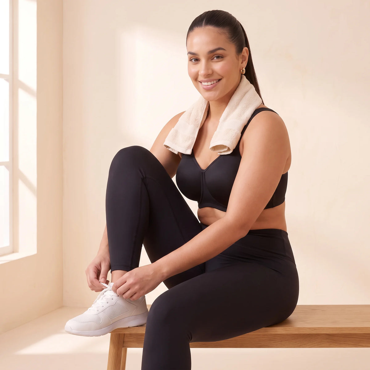 Woman lacing her trainers on a bench after a workout in the Noir black Kischt Léonie underwire sports bra