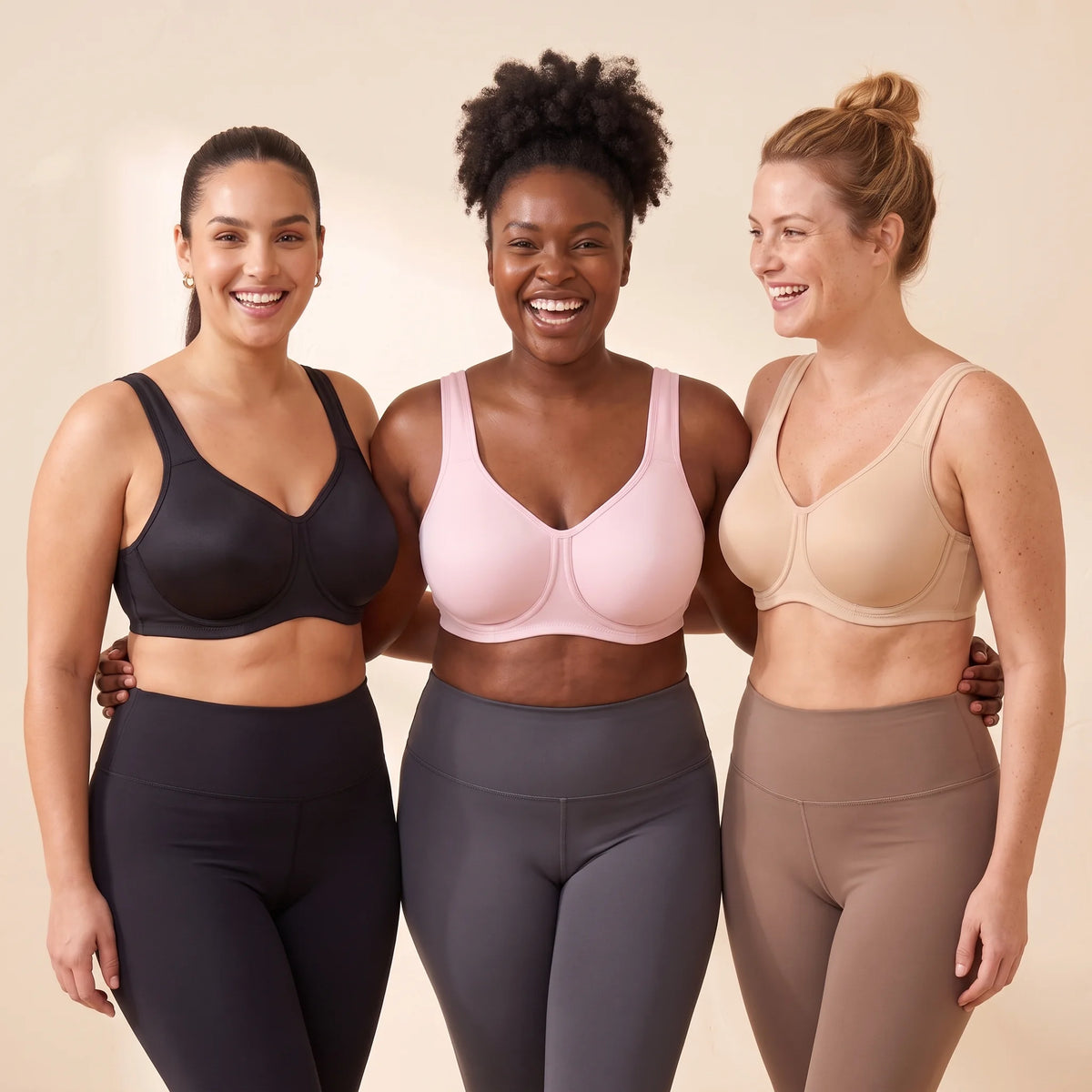 Three women with fuller busts wearing Kischt Léonie underwire sports bras in Noir black, Blush pink and Crème nude