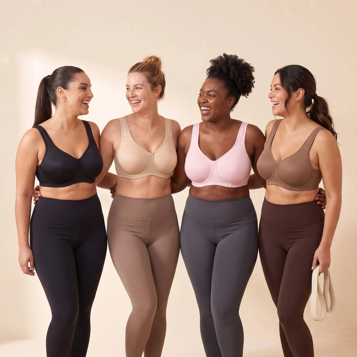 Four women with fuller busts wearing Kischt Léonie high impact underwire sports bras in Noir, Crème, Blush and Mocha