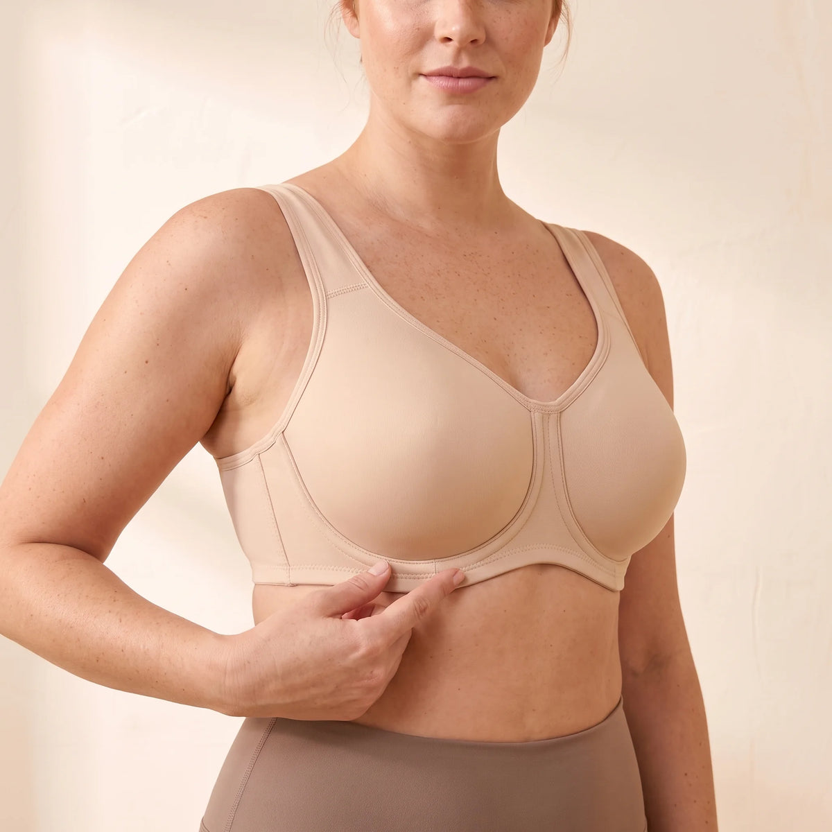 Close-up of the Crème nude beige Kischt Léonie sports bra showing the underwire sewn on the outside of each full-coverage cup