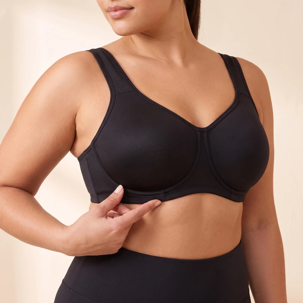 Close-up of the Noir black Kischt Léonie sports bra showing the underwire sewn on the outside of each full-coverage cup