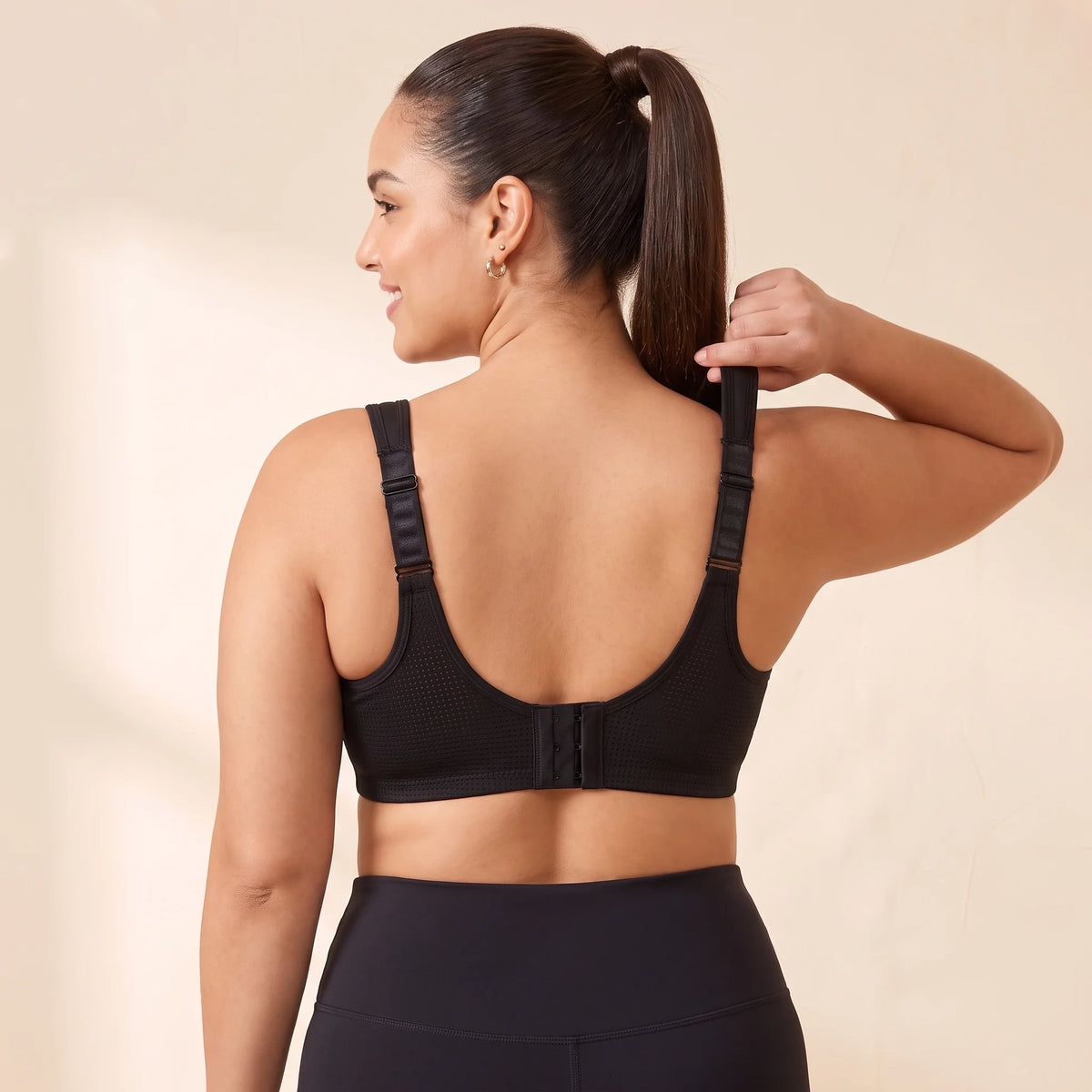 Back view of the Noir black Kischt Léonie sports bra with wide ladder-adjustable straps, a breathable mesh back and a hook-and-eye closure
