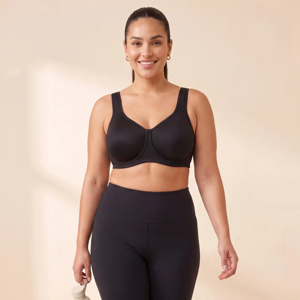 Woman with a full bust mid-stride in the Kischt Léonie high impact underwire sports bra in Noir black with black high-waisted leggings