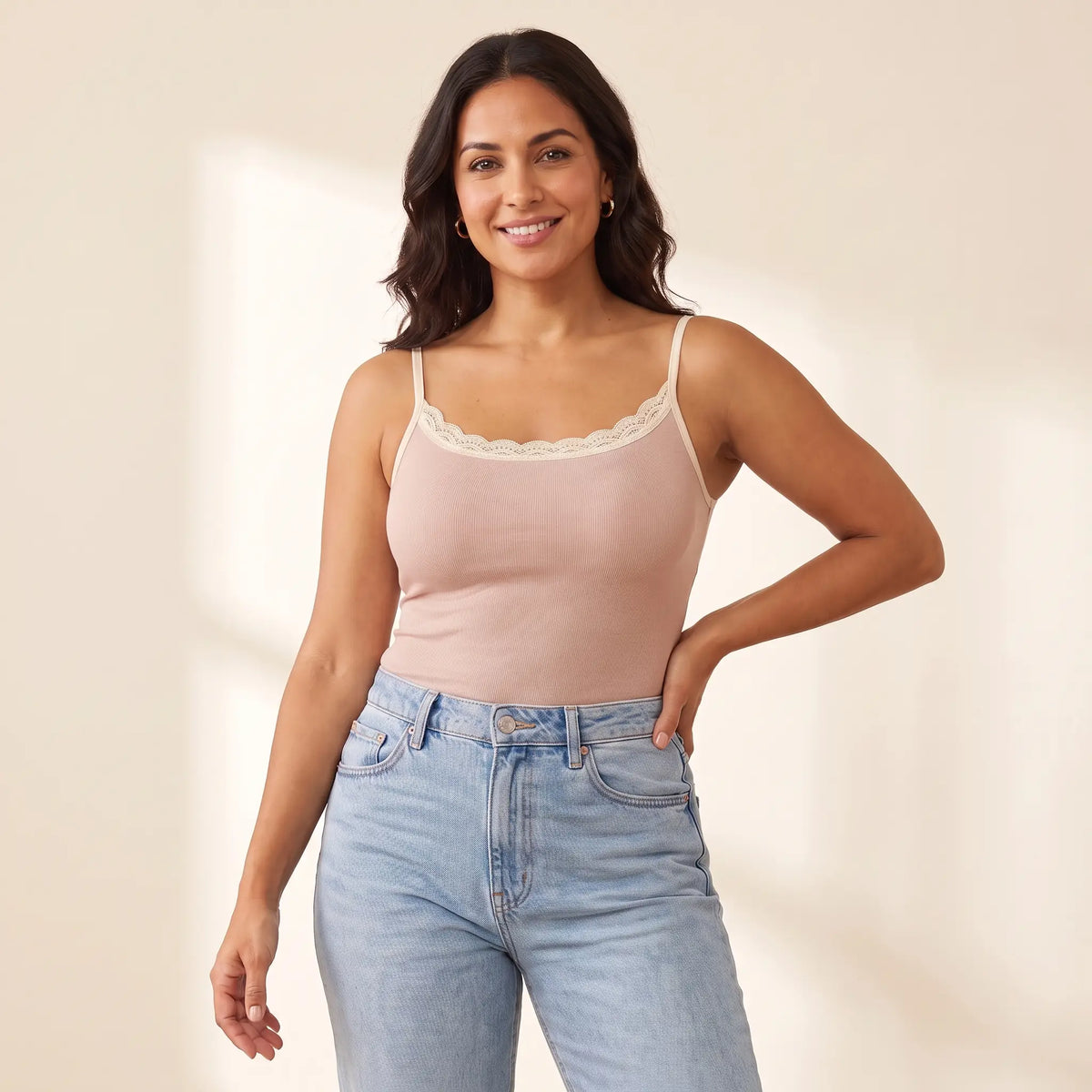 Woman in her 30s wearing the Kischt Lisette lace trim ribbed cami with built-in bra in Poudre blush pink with high-waisted jeans
