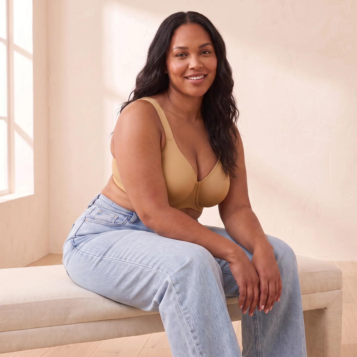 Smiling curvy woman sitting on a bench in jeans and the Almond tan Kischt Margaux full coverage unlined minimizer bra