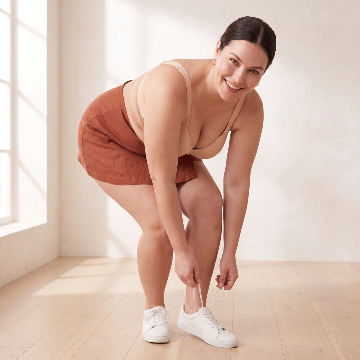 Curvy woman bending to tie her trainers in the Crème nude Kischt Margaux full coverage bra, with everything staying in place
