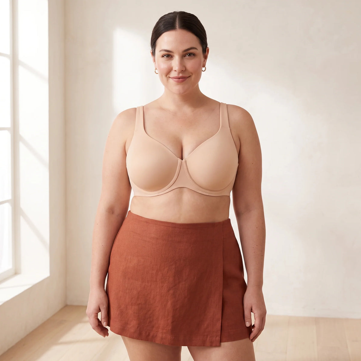 Curvy woman with a sleek bun wearing the Kischt Margaux full coverage unlined minimizer bra in Crème nude beige with a rust linen skirt