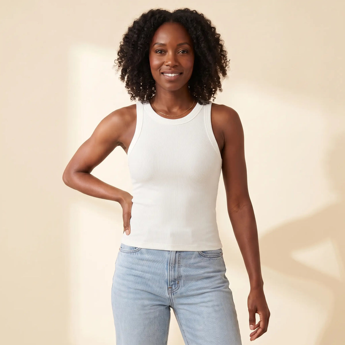 Woman in her 30s wearing the Kischt Noemi ribbed racerback tank top with built-in bra in Blanc white with high-waisted jeans