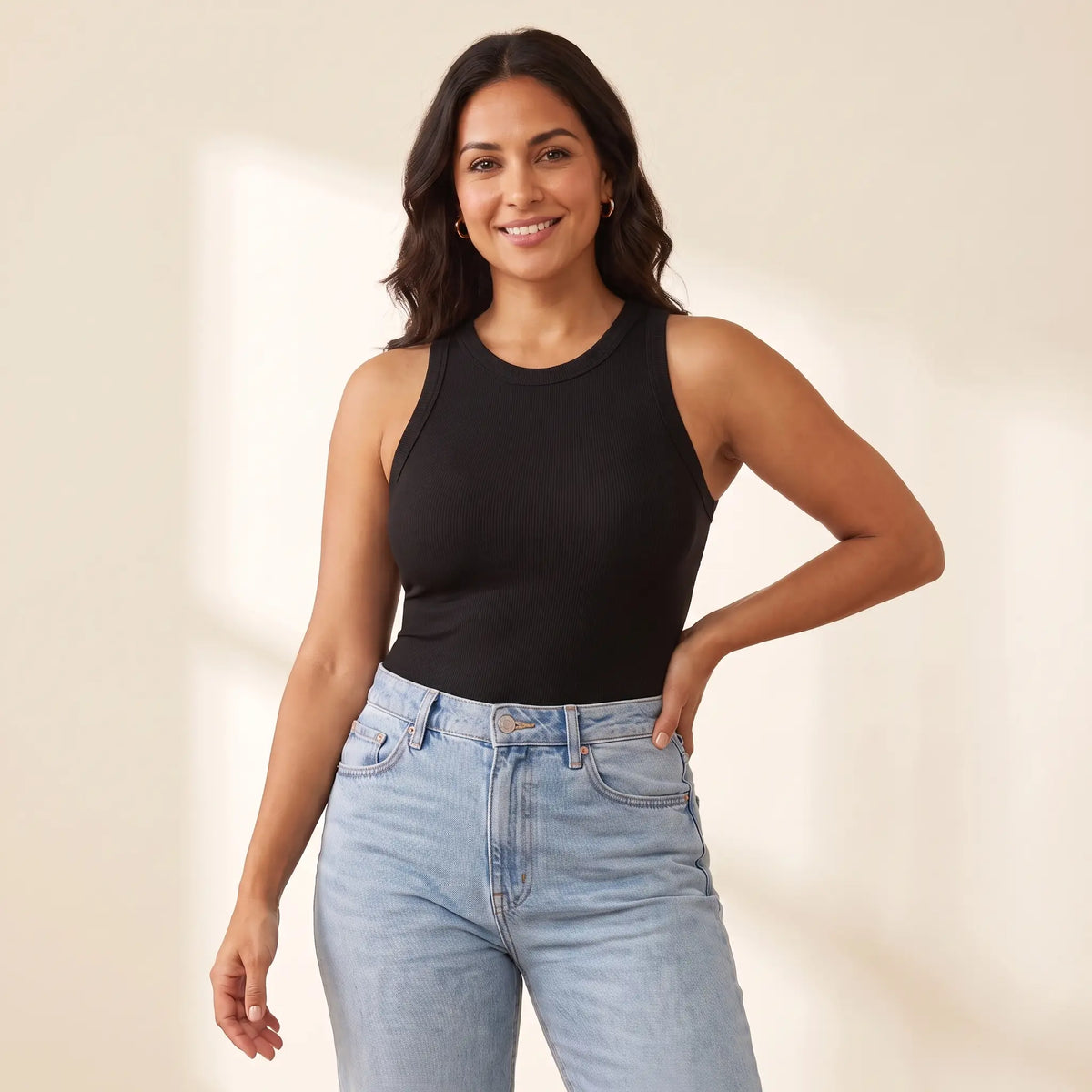 Woman in her 30s wearing the Kischt Noemi ribbed racerback tank top with built-in bra in Noir black with high-waisted jeans