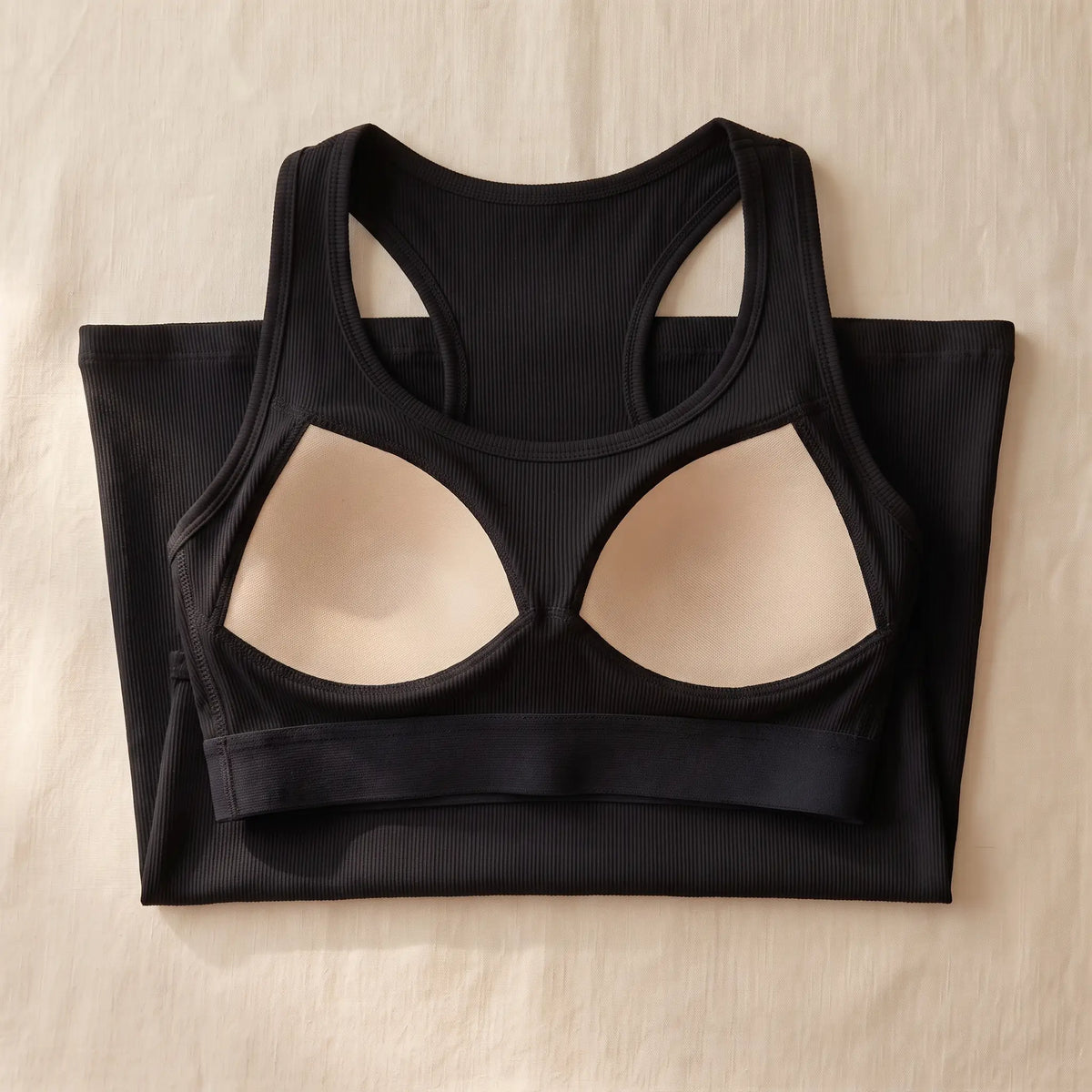 Inside of the Noir black Kischt Noemi racerback tank top: a built-in bra layer with soft padded cups and an elastic underbust band, no underwire