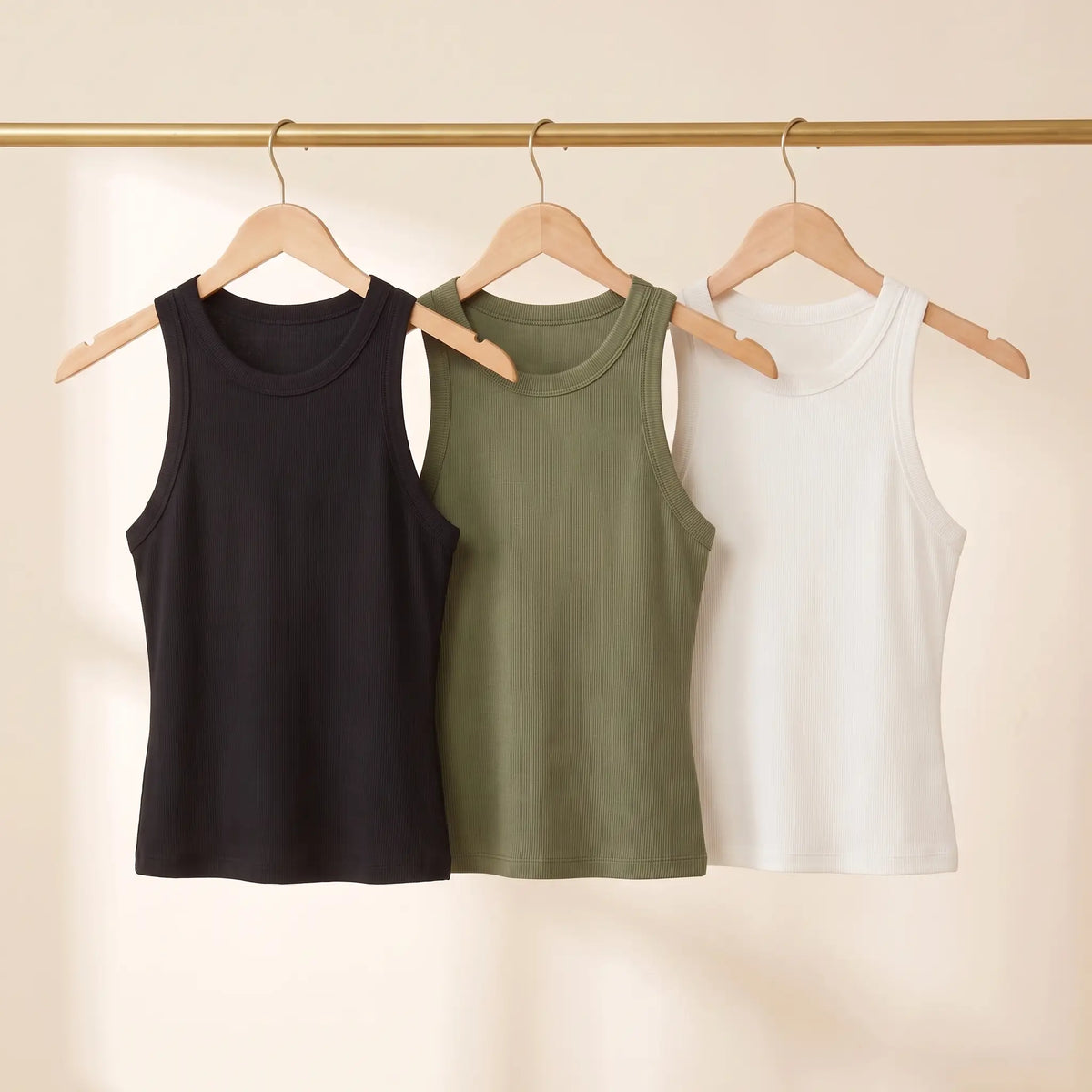 All three Kischt Noemi ribbed racerback built-in bra tank top colours on a rail: black, army green and white