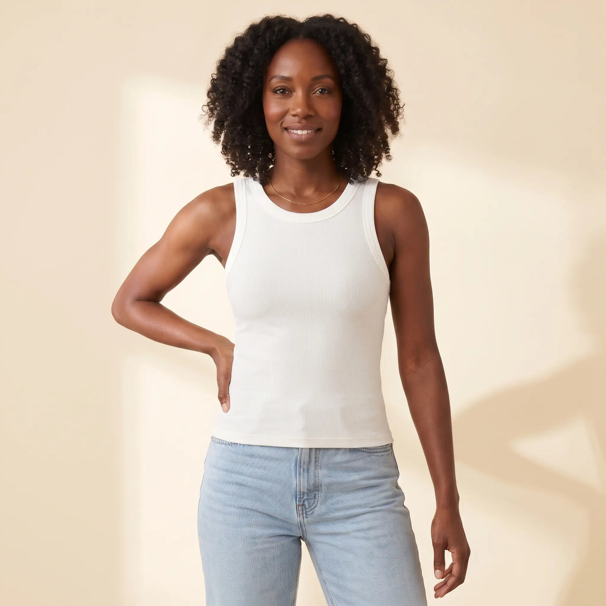 Woman in her 30s wearing the Kischt Solene ribbed crew neck tank top with built-in bra in Blanc white with high-waisted jeans