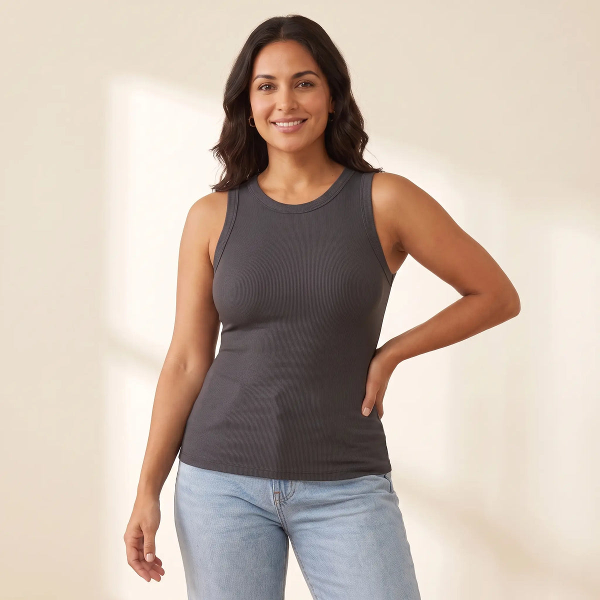 Woman in her 30s wearing the Kischt Solene ribbed crew neck tank top with built-in bra in Graphite dark grey with high-waisted jeans