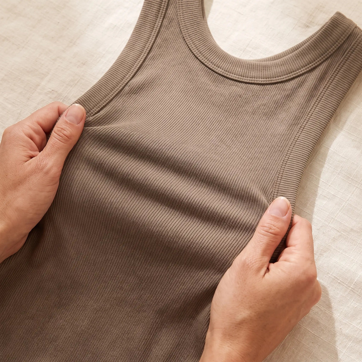 Hands stretching the soft rib knit of the Sable khaki Kischt Solene tank top